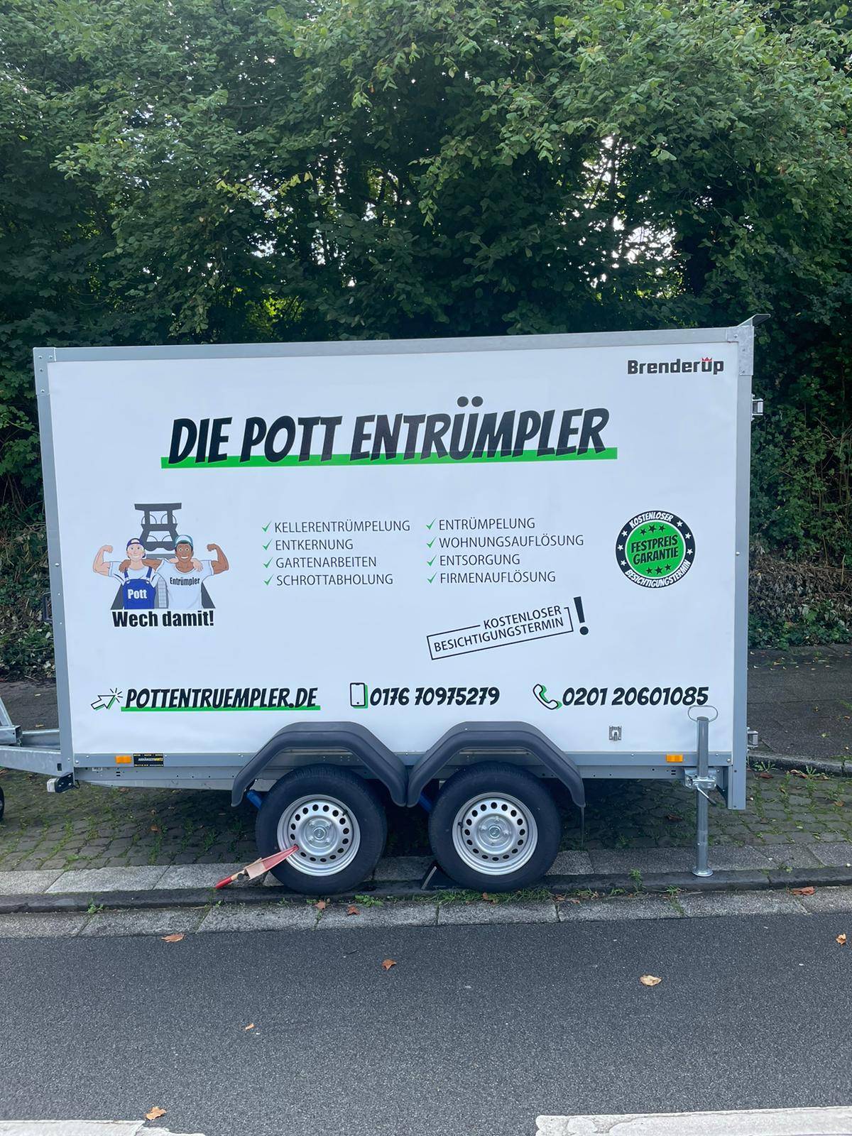 Gerne! Hier ist der überarbeitete Text, passend für pottentruempler.de und optimiert auf das Hauptkeyword "Entrümpelung": --- Ein Anhänger mit Die Pott Entrümpler-Branding wirbt direkt vor Ort für professionelle Entrümpelung. Ob Kellerentrümpelung, Gartenentrümpelung oder Wohnungsauflösungen - auf dem Anhänger werden alle Entrümpelungsdienste übersichtlich präsentiert. Das auffällige Design zeigt nicht nur die Kontaktdaten und Social-Media-Icons, sondern auch das sympathische Cartoon-Teamlogo von Die Pott Entrümpler. Geparkt neben einer Straße sowie grünen Büschen macht der Anhänger auf unsere umfassenden Entrümpelungsservices im Ruhrgebiet aufmerksam. --- Gern passe ich den Text weiter an individuelle Wünsche an!. Gerne! Hier ist der überarbeitete Text, passend für pottentruempler.de und optimiert auf das Hauptkeyword "Entrümpelung": --- Ein Anhänger mit Die Pott Entrümpler-Branding wirbt direkt vor Ort für professionelle Entrümpelung. Ob Kellerentrümpelung, Gartenentrümpelung oder Wohnungsauflösungen - auf dem Anhänger werden alle Entrümpelungsdienste übersichtlich präsentiert. Das auffällige Design zeigt nicht nur die Kontaktdaten und Social-Media-Icons, sondern auch das sympathische Cartoon-Teamlogo von Die Pott Entrümpler. Geparkt neben einer Straße sowie grünen Büschen macht der Anhänger auf unsere umfassenden Entrümpelungsservices im Ruhrgebiet aufmerksam. --- Gern passe ich den Text weiter an individuelle Wünsche an!.