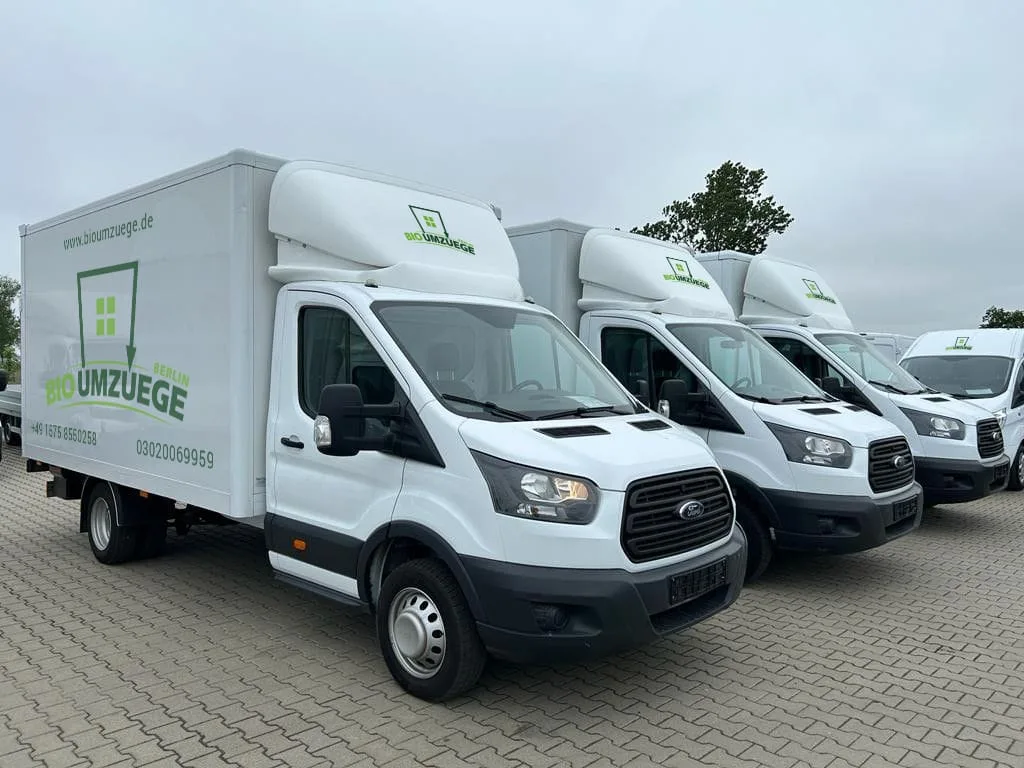 Vier weiße Transporter mit der Aufschrift "BIO UMZUEGE" und einem grünen Logo an der Seite stehen sauber und einheitlich in einer Reihe auf einem gepflasterten Parkplatz - bereit für Ihre professionelle Entrümpelung. Die Fahrzeuge sind identisch, gepflegt und zeigen, wie zuverlässig unsere Entrümpelungs-Services von Pottentruempler.de arbeiten. Ganz gleich ob Wohnung, Haus oder Keller: Mit moderner Fahrzeugflotte unterstreichen wir unsere Kompetenz als Partner für nachhaltige Entrümpelung im Ruhrgebiet - auch bei wolkigem Himmel immer einsatzbereit!. Vier weiße Transporter mit der Aufschrift "BIO UMZUEGE" und einem grünen Logo an der Seite stehen sauber und einheitlich in einer Reihe auf einem gepflasterten Parkplatz - bereit für Ihre professionelle Entrümpelung. Die Fahrzeuge sind identisch, gepflegt und zeigen, wie zuverlässig unsere Entrümpelungs-Services von Pottentruempler.de arbeiten. Ganz gleich ob Wohnung, Haus oder Keller: Mit moderner Fahrzeugflotte unterstreichen wir unsere Kompetenz als Partner für nachhaltige Entrümpelung im Ruhrgebiet - auch bei wolkigem Himmel immer einsatzbereit!.